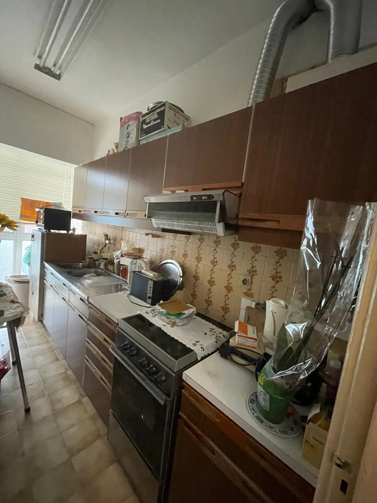 Cozinha antiga com móveis castanhos e azulejo datado antes da remodelação